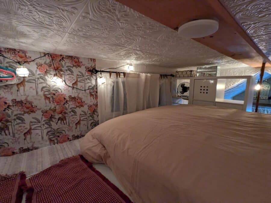 Charming tiny house bedroom featuring vintage floral wallpaper and a comfortable bed, perfect for a.