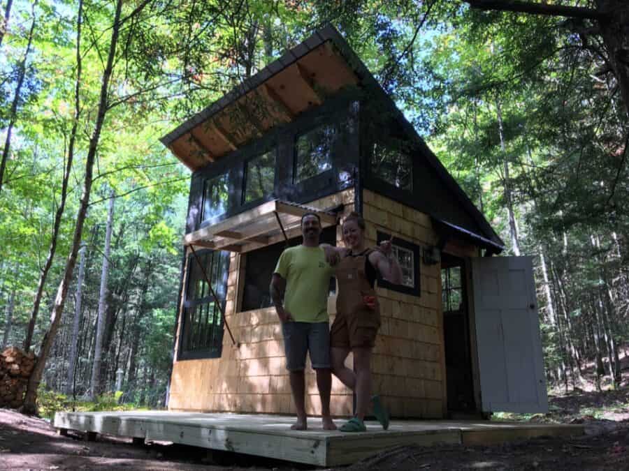 Tiny house on a wooden platform in a forest setting.