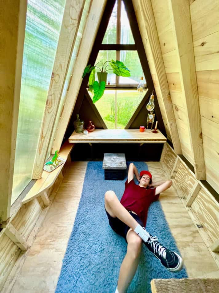 Small wooden tiny house interior with cozy nook and large window.