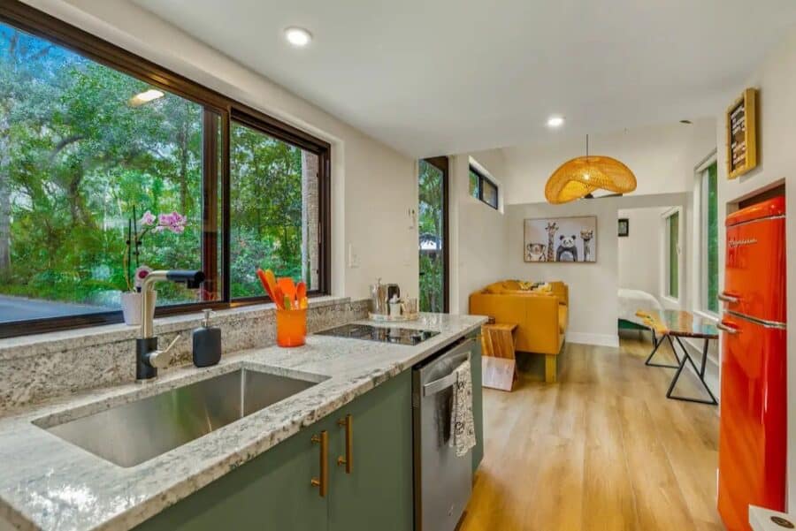 Bright tiny house kitchen featuring large windows overlooking lush greenery in Thonotosassa, Florida.