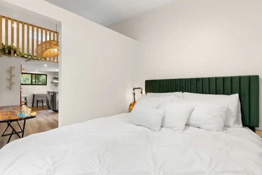 Comfortable tiny house bedroom with white bedding and green headboard in a peaceful Florida setting.