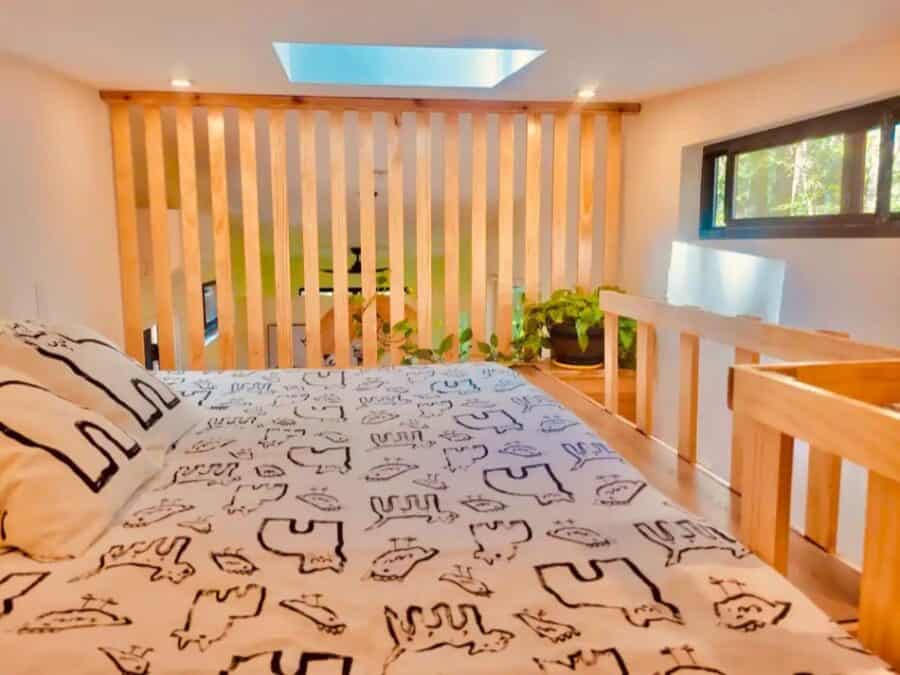 Cozy tiny house bedroom with natural wood accents and large window views.