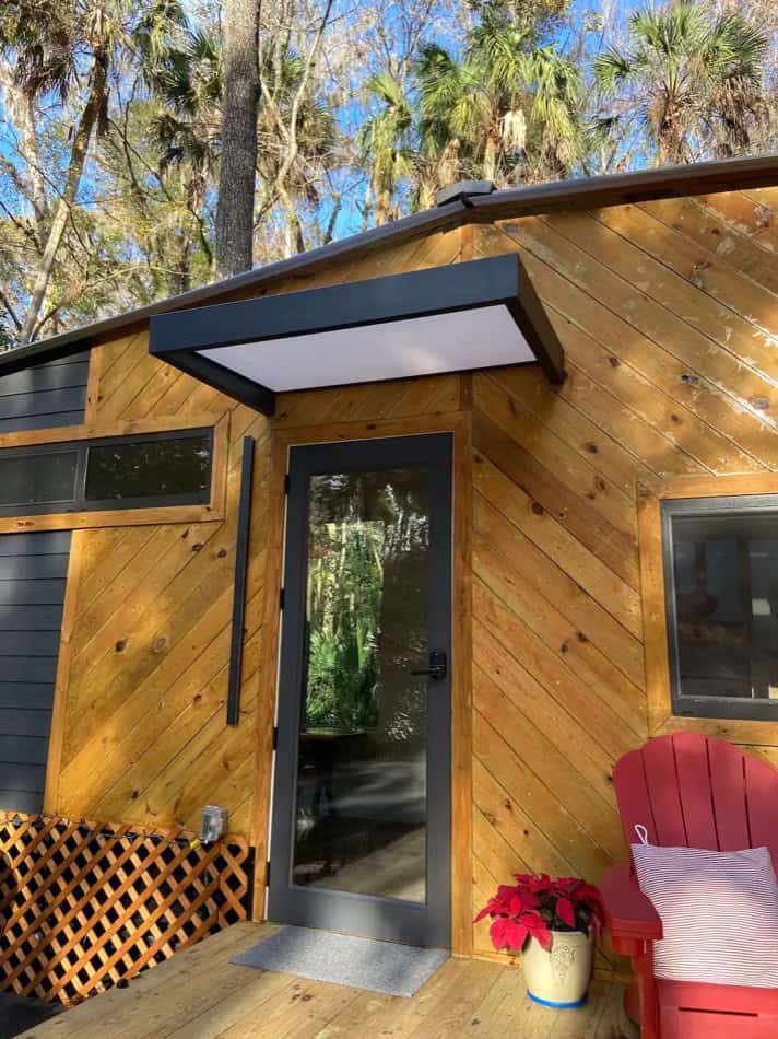 Charming tiny house with wooden exterior nestled among palm trees in Thonotosassa, Florida.