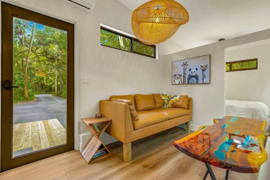 Bright interior of a tiny house with a tan sofa and colorful decor.