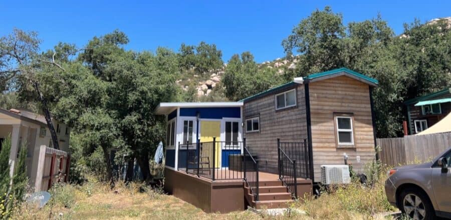 Tiny house with an elevated deck, modern design, and natural wooded backdrop. Perfect for small spac.