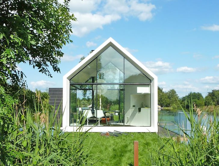 Glass cabin exterior on a narrow Dutch island surrounded by lake water and lush greenery
