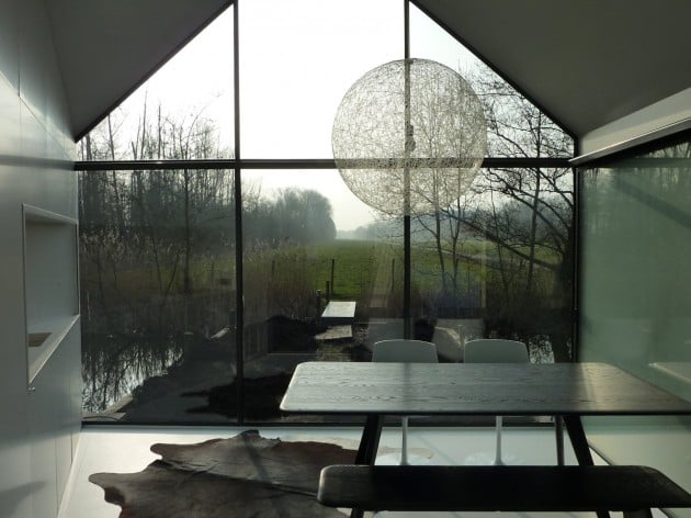View from the raised dining platform through the glass gable end wall with sphere pendant light and misty lake view