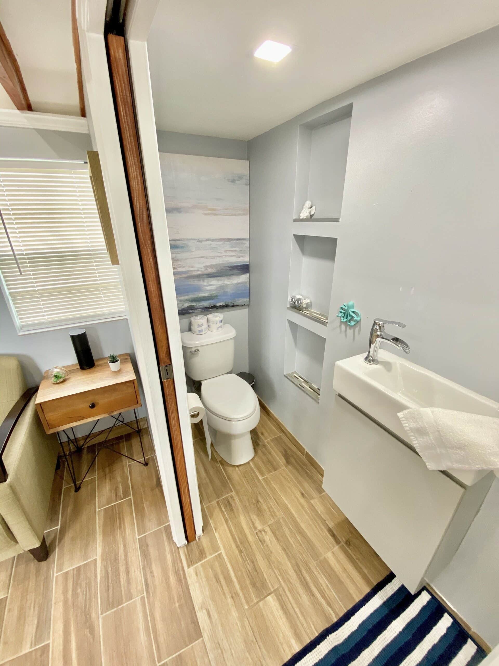 Bathroom with sliding barn door, built-in shelves, ocean art, and wall-mounted sink