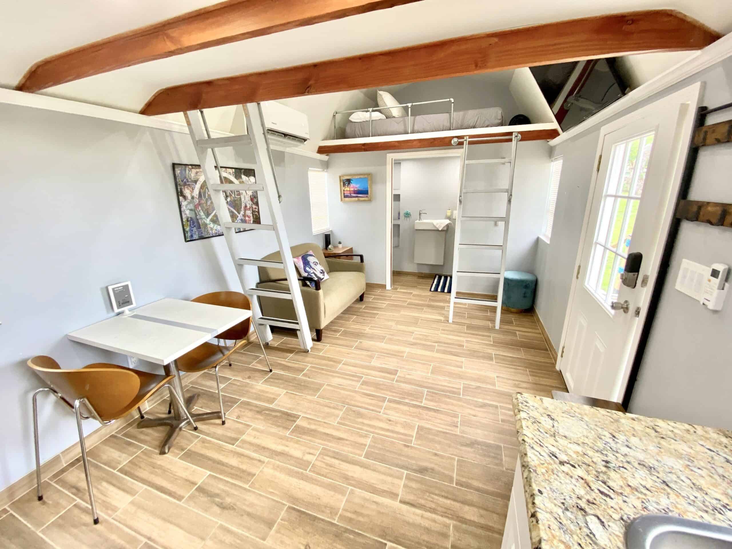 Full interior view of the tiny lake cottage showing loft bedroom, kitchen, dining, and living area