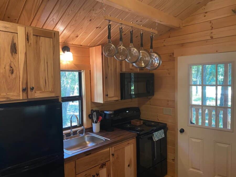 Charming tiny log cabin kitchen with wooden cabinets and modern appliances.