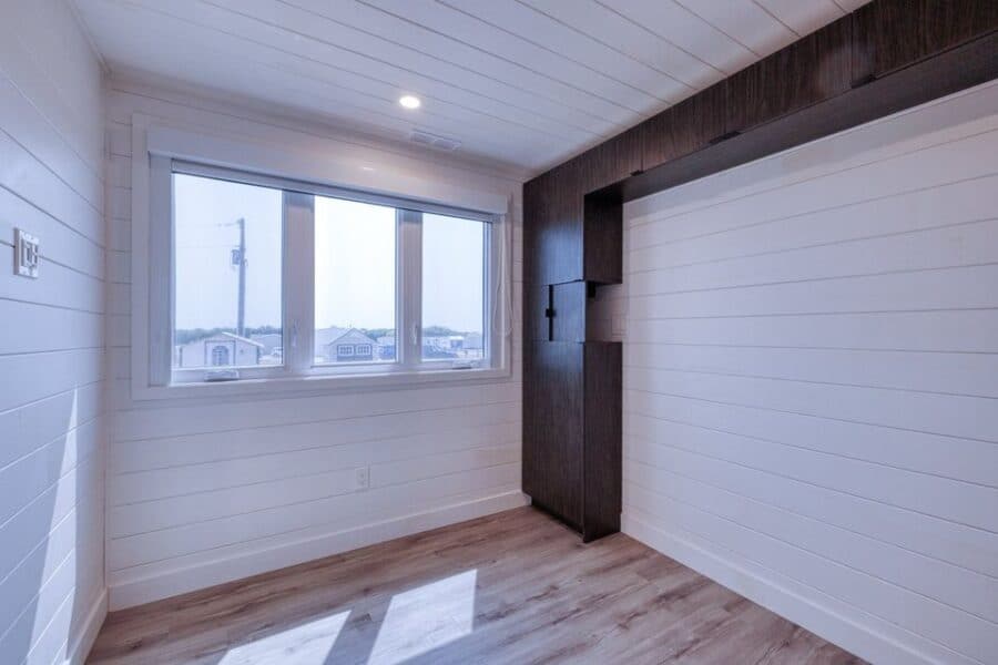 Interior of a tiny house with white shiplap walls and large window in Decatur, Texas.
