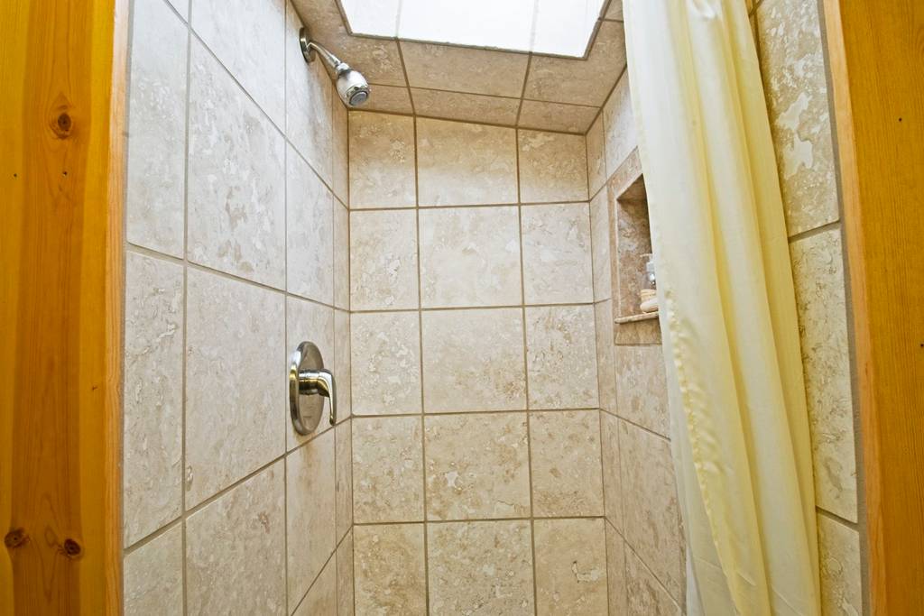 Travertine shower in compact bathroom area
