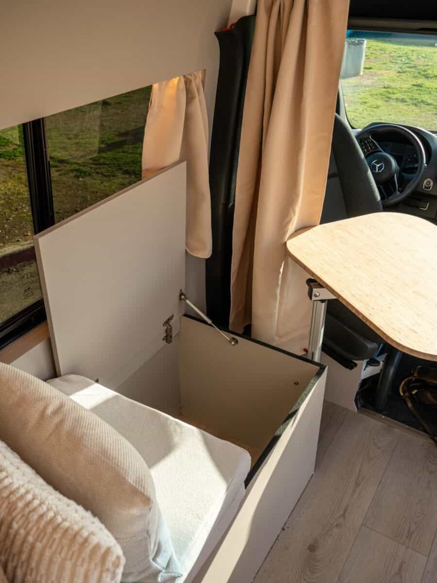 Interior view of a van conversion with a cozy sleeping area and small dining table.