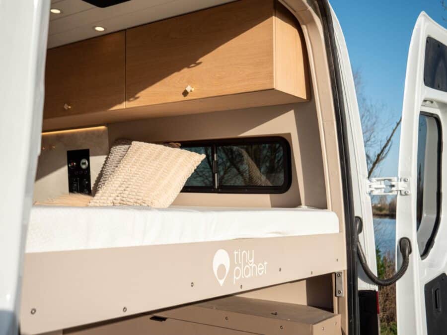 Van conversion interior with custom storage and cozy sleeping area.