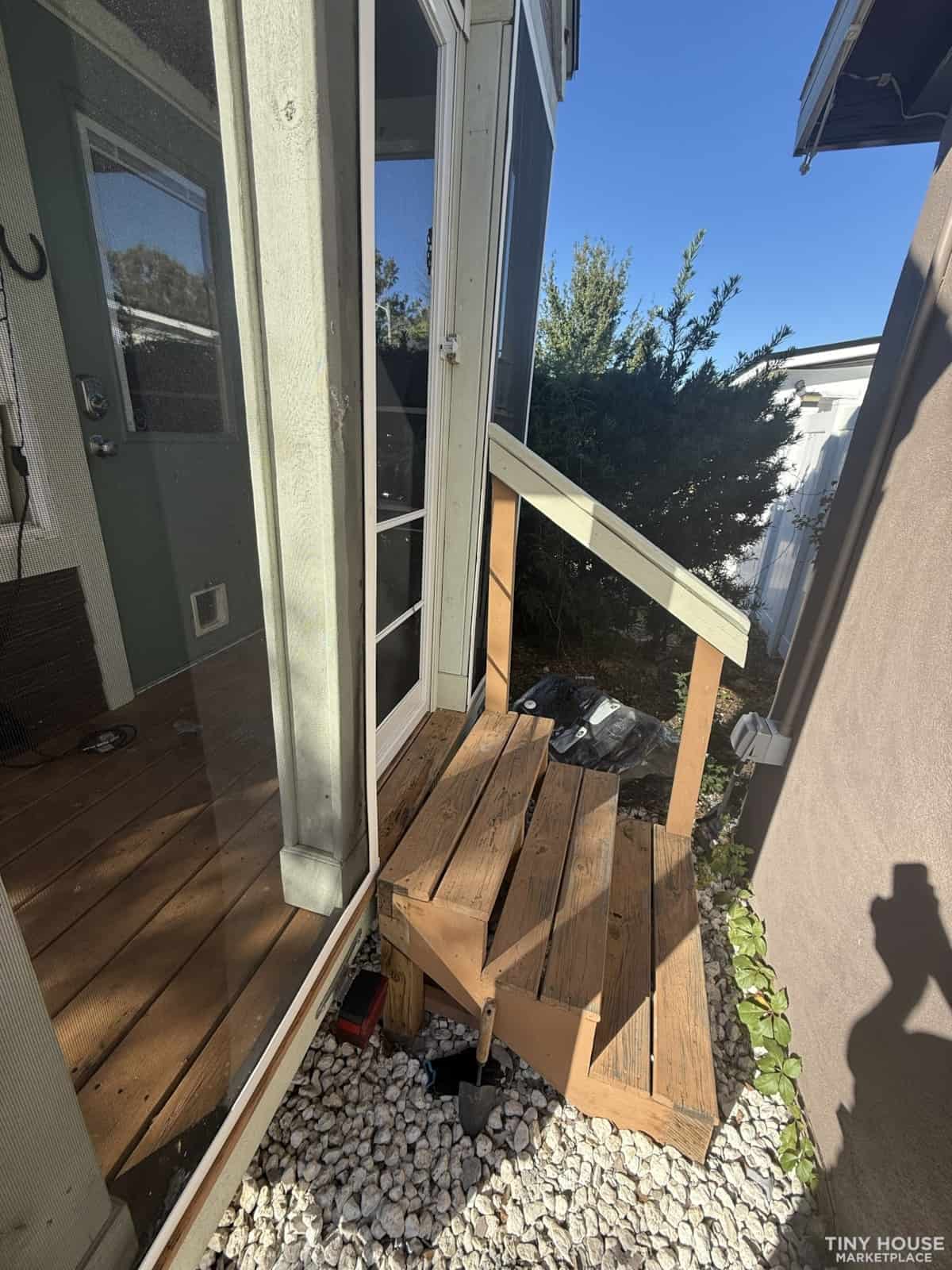 Wooden step stool outside tiny house for easy entry and exit.