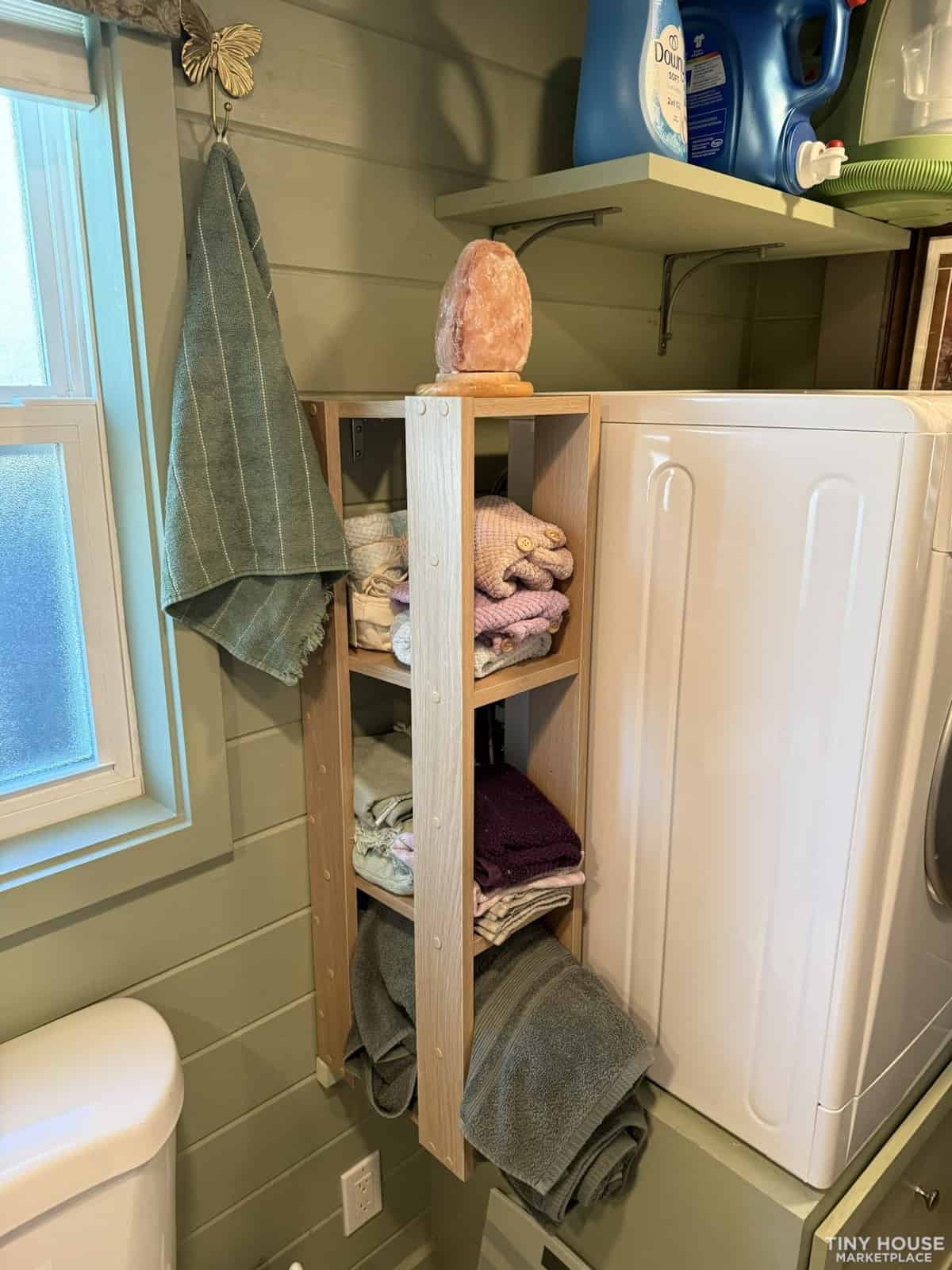 Efficient laundry organization with open shelving for towels and linens in small space.