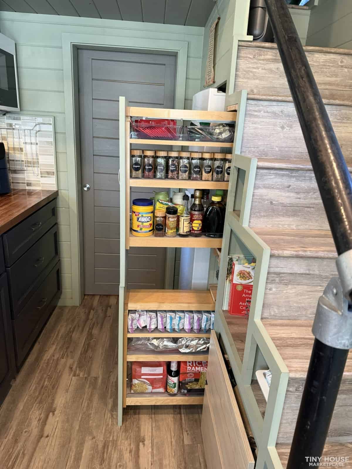 Full pull-out pantry storage built into the staircase with multiple shelves of spices and food