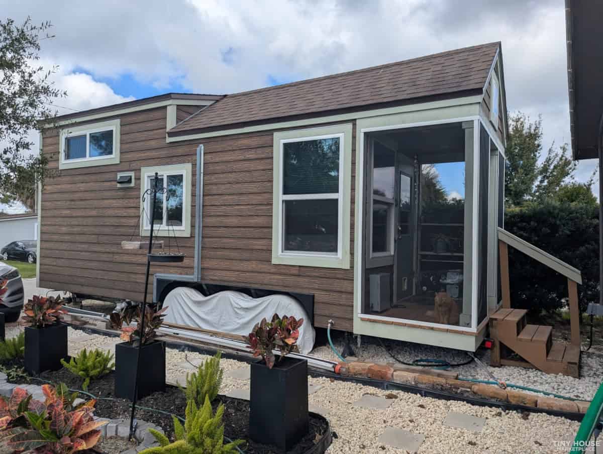 Charming tiny house featuring a compact, modern design with large windows and a cozy porch. Perfect.