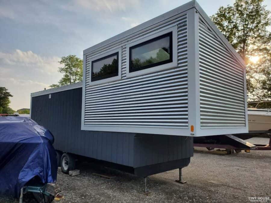 Compact gooseneck tiny house on wheels with modern exterior design.
