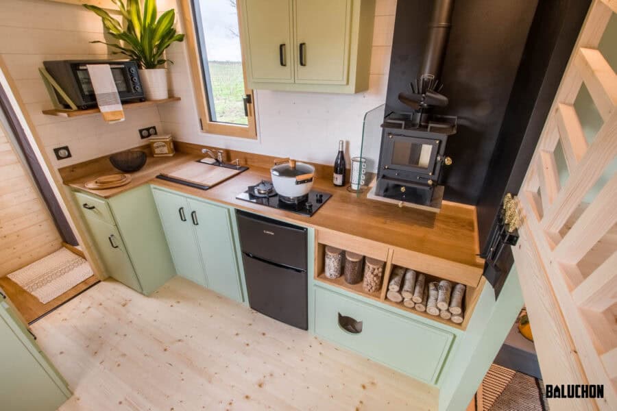 Compact tiny house kitchen with creative flex room loft for versatile living space.