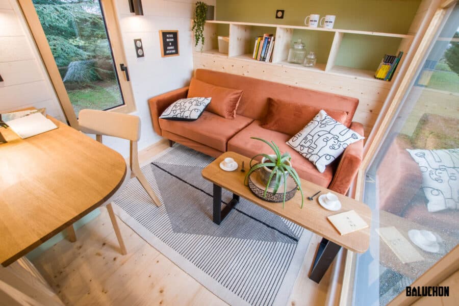 Small living space with a rust-colored sofa, wooden table, and built-in shelves.