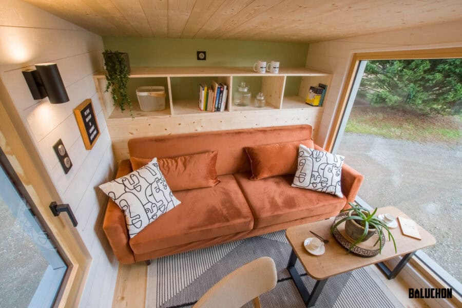 Cozy living area in a tiny house featuring a comfortable sofa and creative loft space for flexible u.
