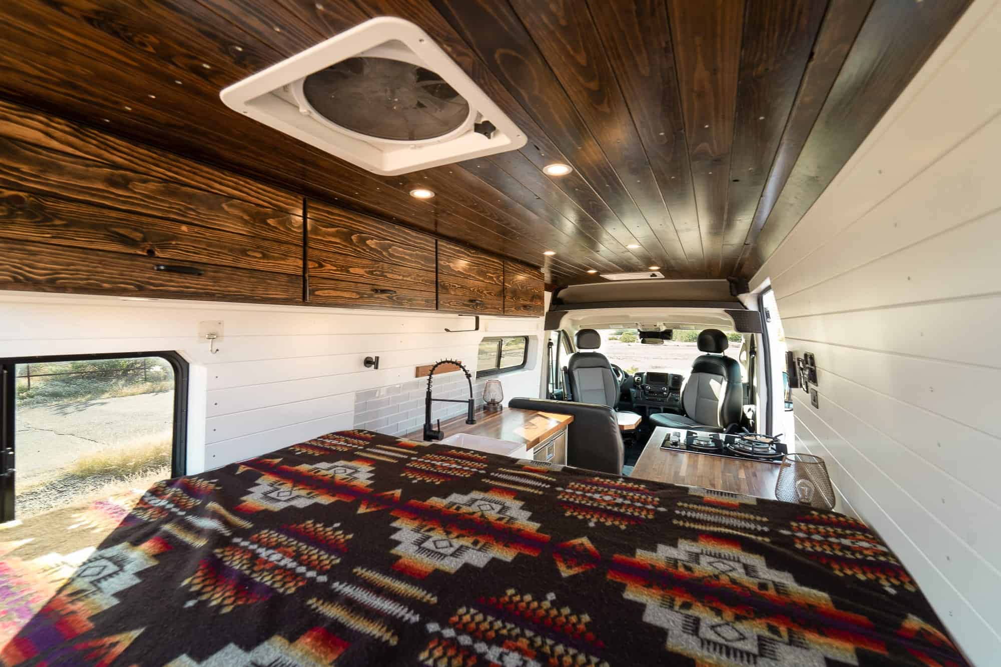 View forward from the rear bed of the ProMaster camper van toward the galley and cab