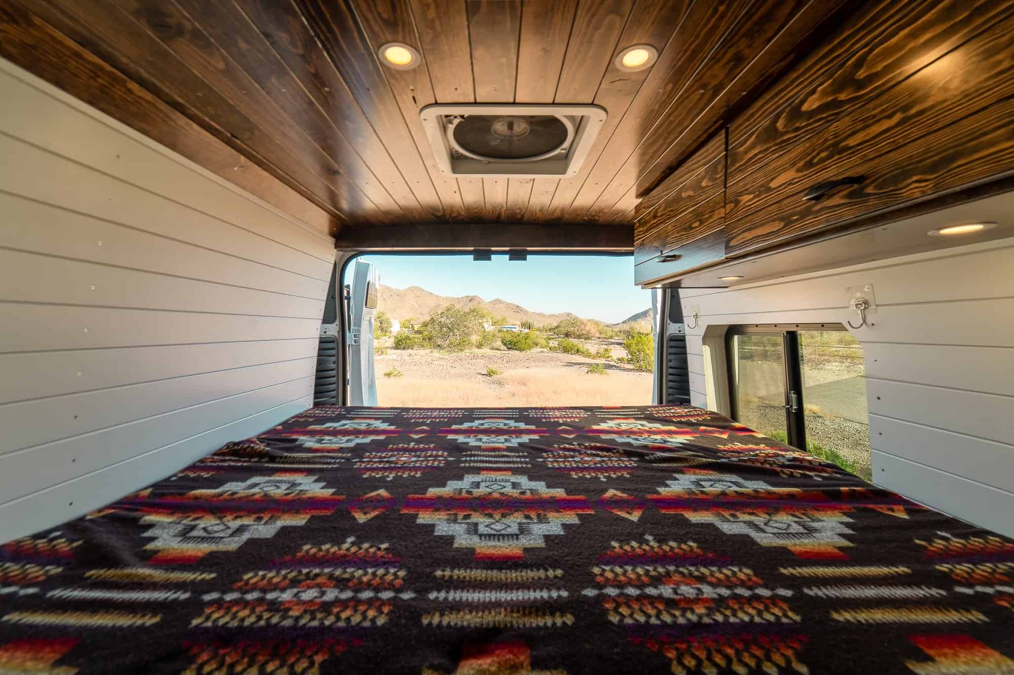 Looking out the open rear doors of the Tommy Camper Vans ProMaster from the fixed bed toward the desert
