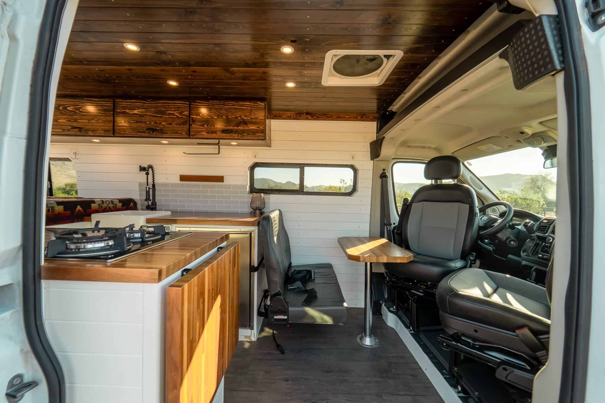 View through the ProMaster galley toward the fixed rear bed with Pendleton-style blanket