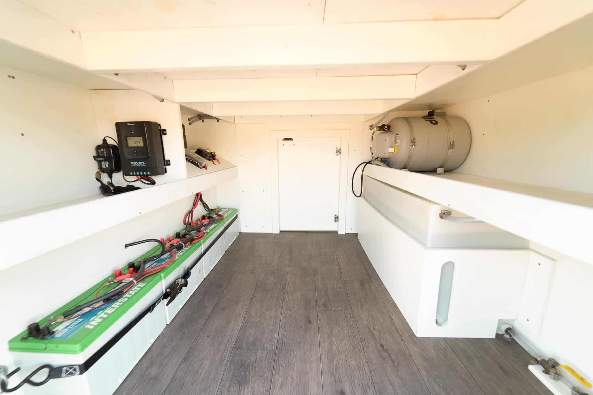 Interior of the ProMaster rear garage showing Interstate batteries, Renogy charge controller, propane tank and fresh water tank