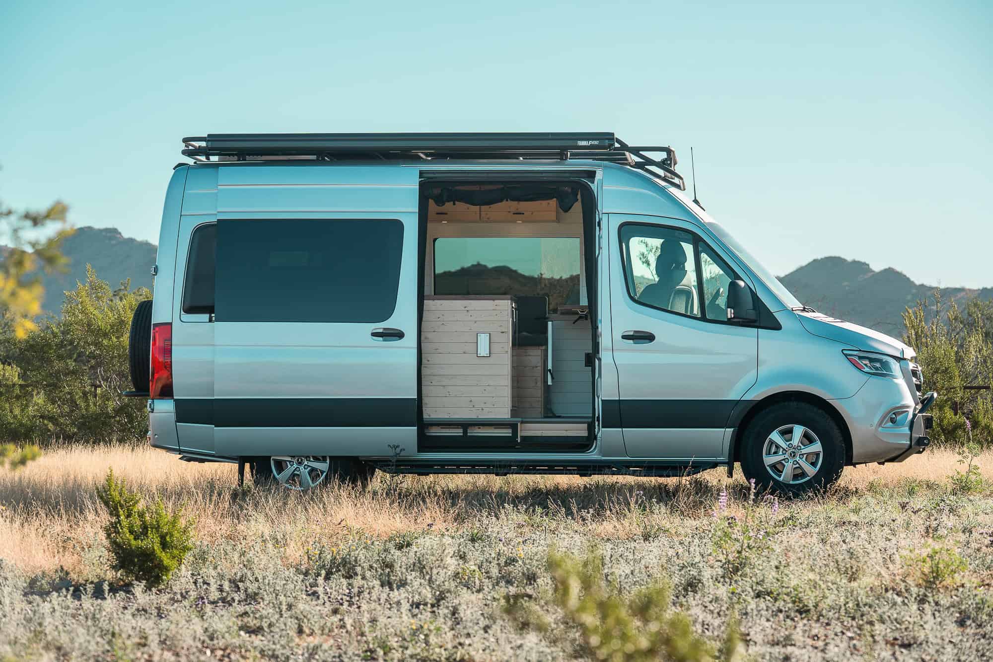 Side profile of the 2024 Sprinter Bennett build showing the roof rack, awning and side step