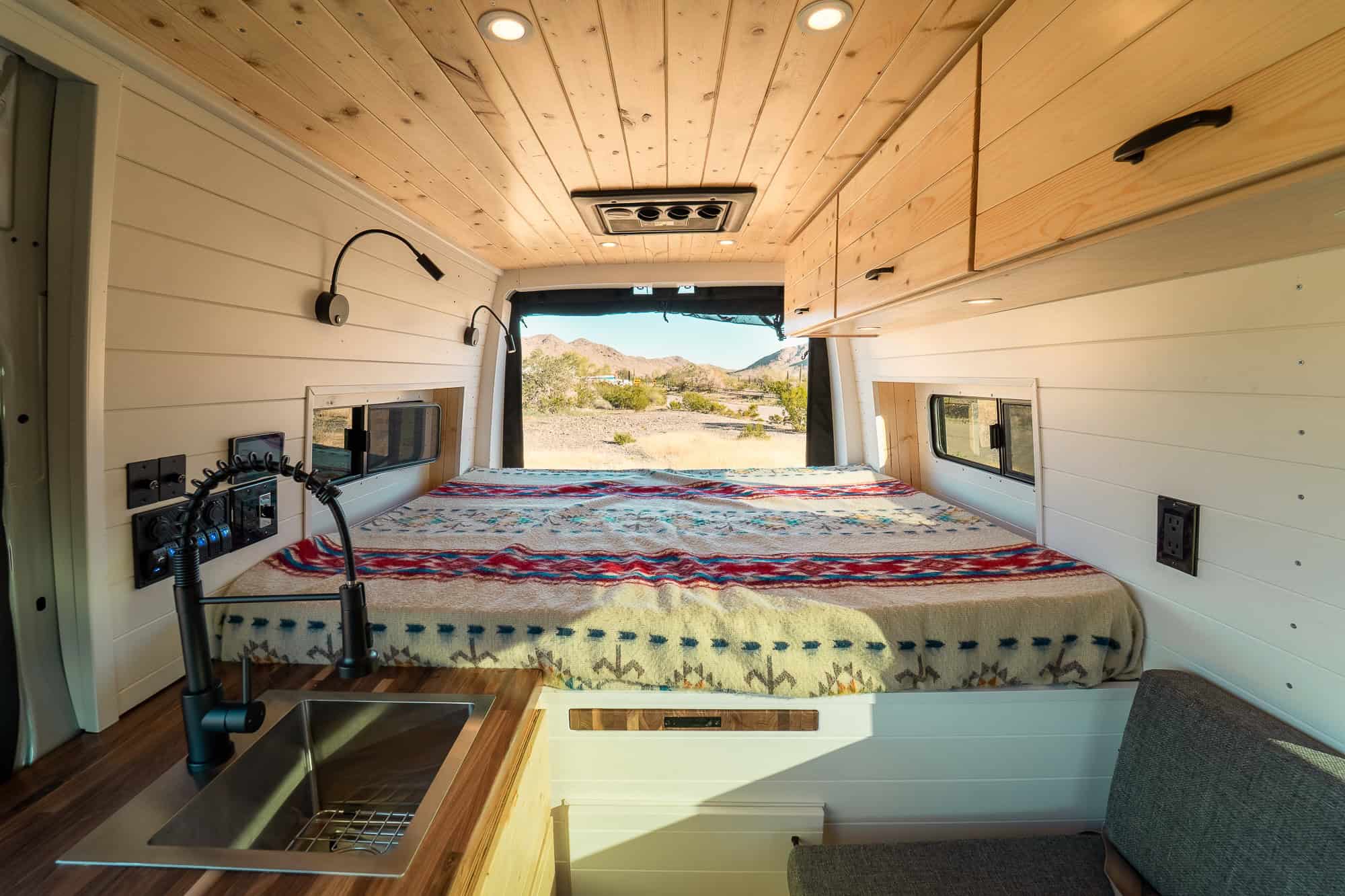 Fixed rear bed with a Pendleton-style wool blanket, reading lights and windows on both sides
