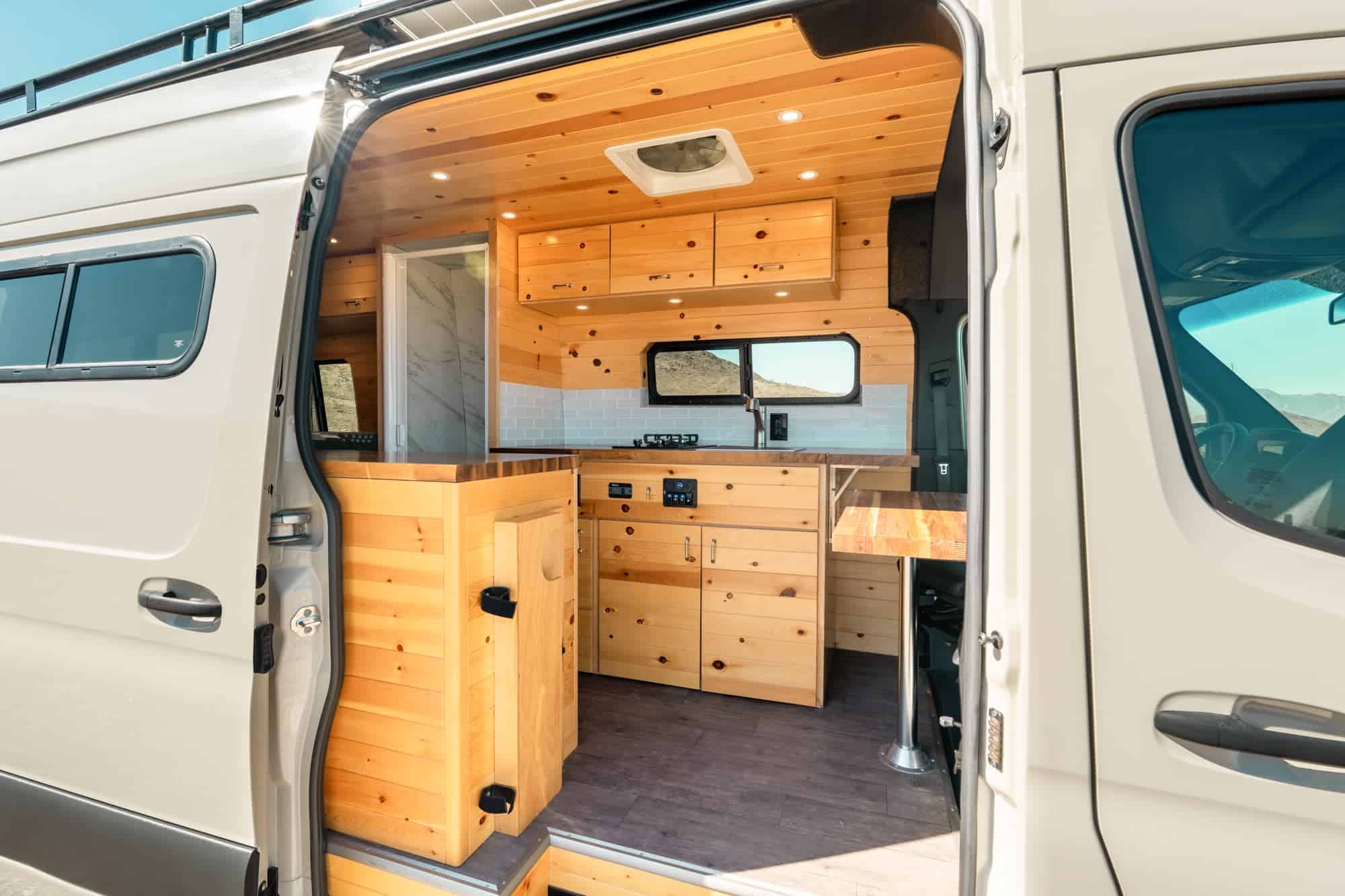 Knotty pine Maddox interior with the marble-look shower enclosure visible beside the galley cabinets