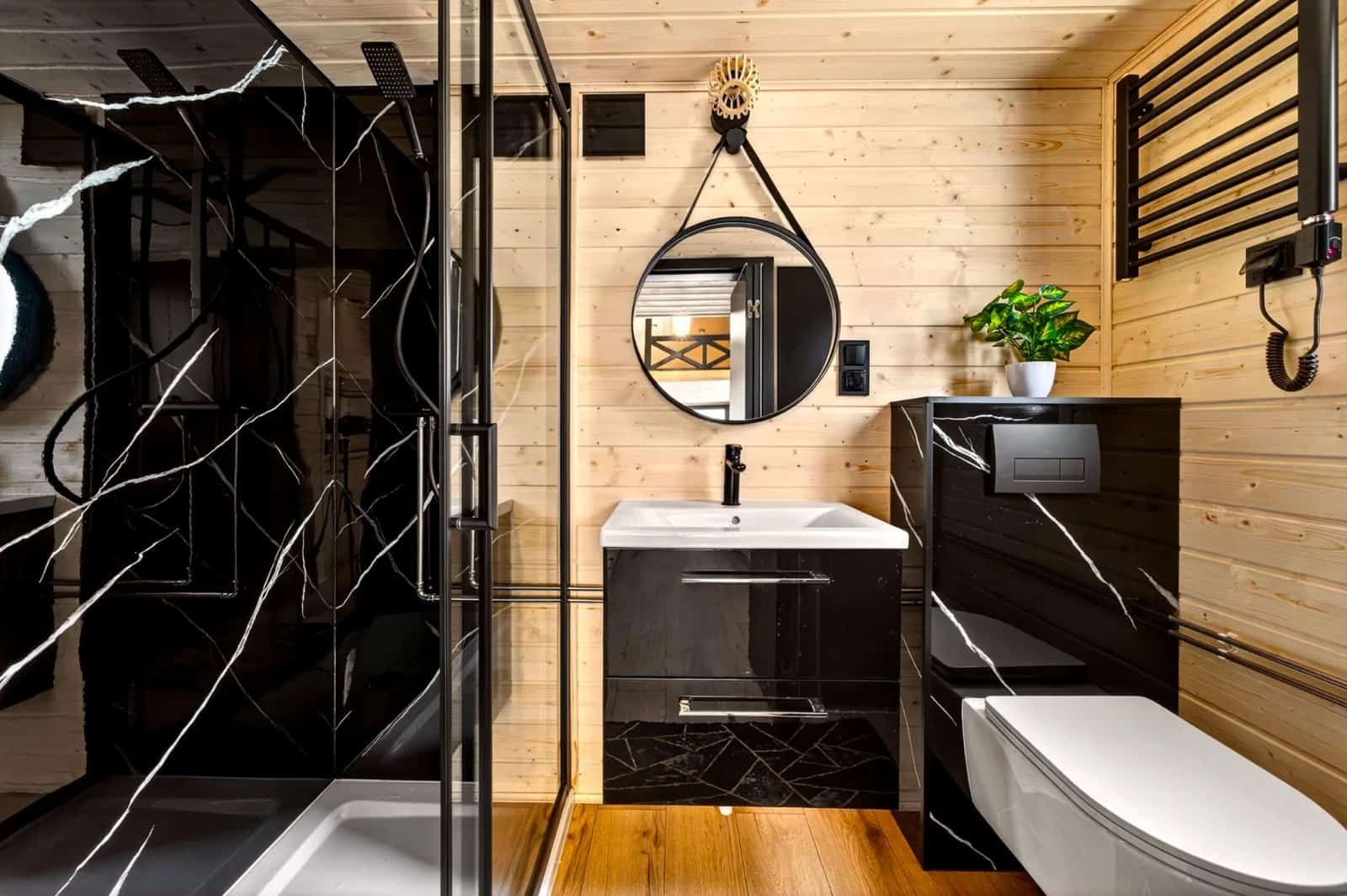 Bathroom in the Tommy tiny house with a black marble walk-in shower, vanity, and wall-hung toilet