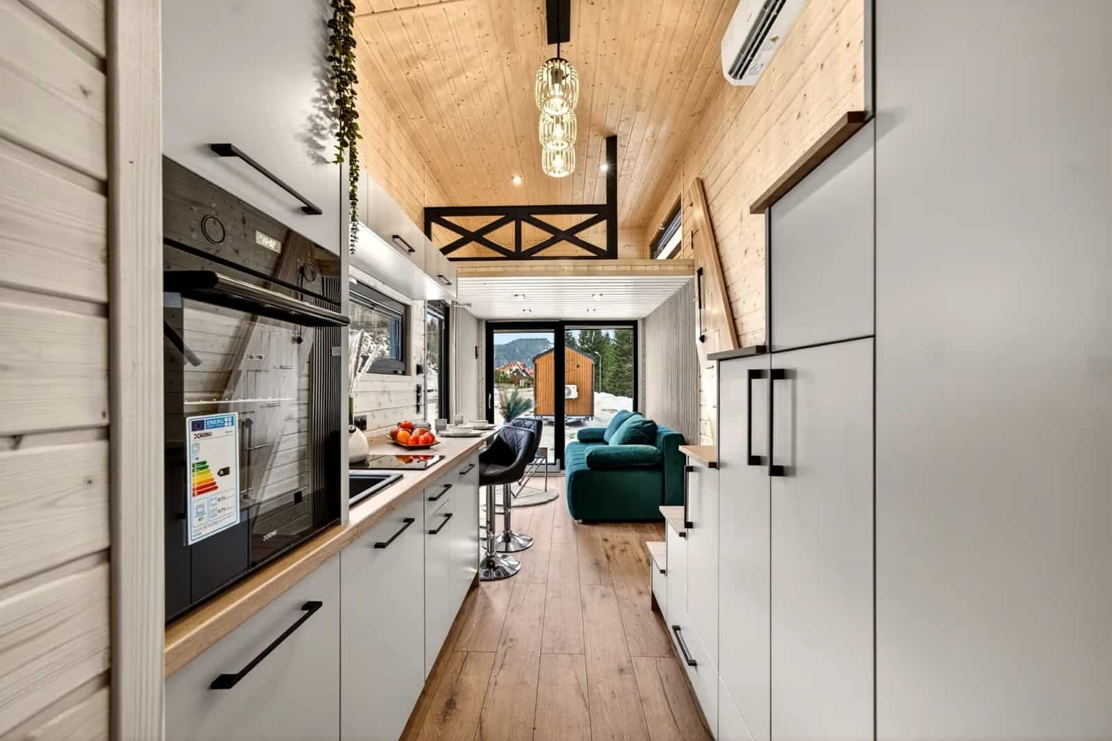 Interior of the Tommy tiny house looking from the kitchen toward the living room and glass doors