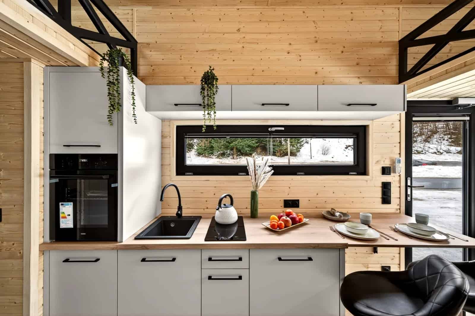Kitchen detail in the Tommy tiny house with a black sink, induction cooktop, and a long picture window