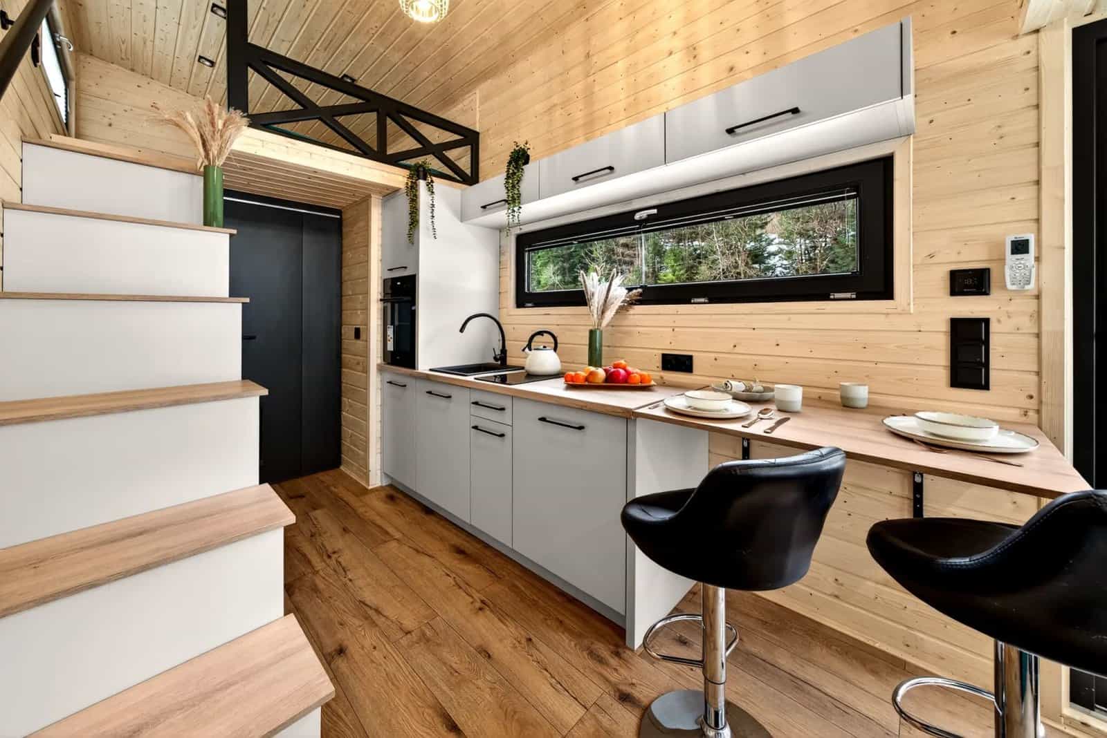 Kitchen, dining bar, and the staircase to the mezzanine inside the Tommy tiny house