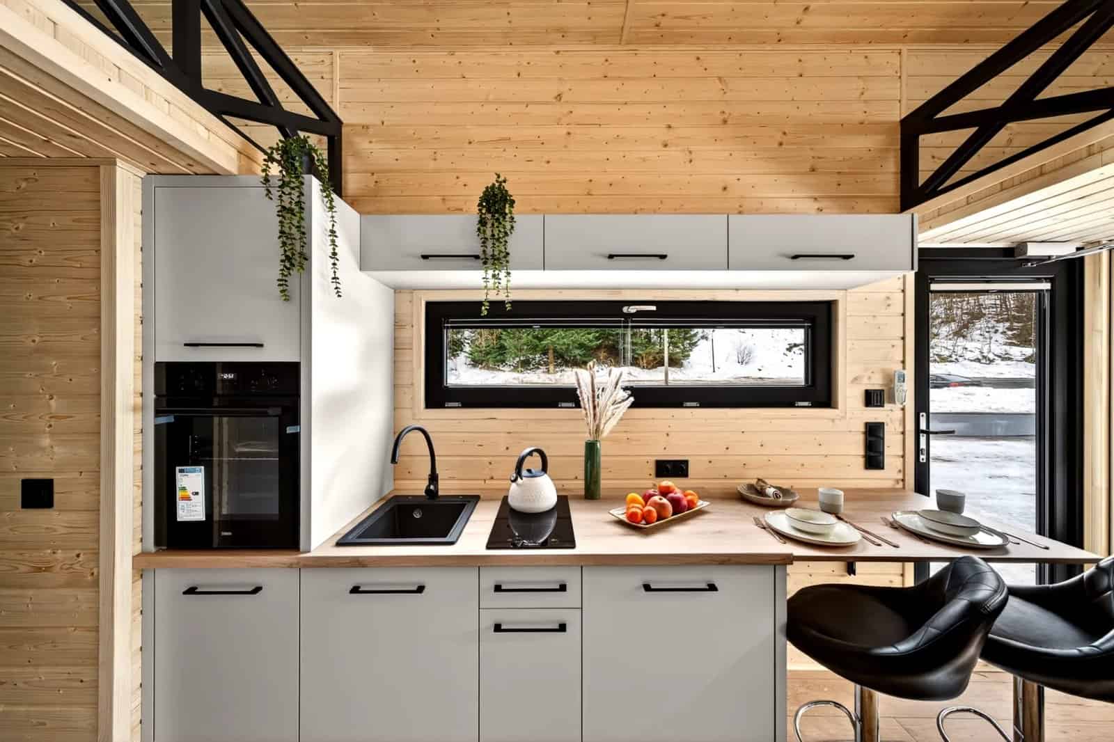 Galley kitchen in the Tommy tiny house with gray cabinets, butcher block counters, an oven, and an induction hob