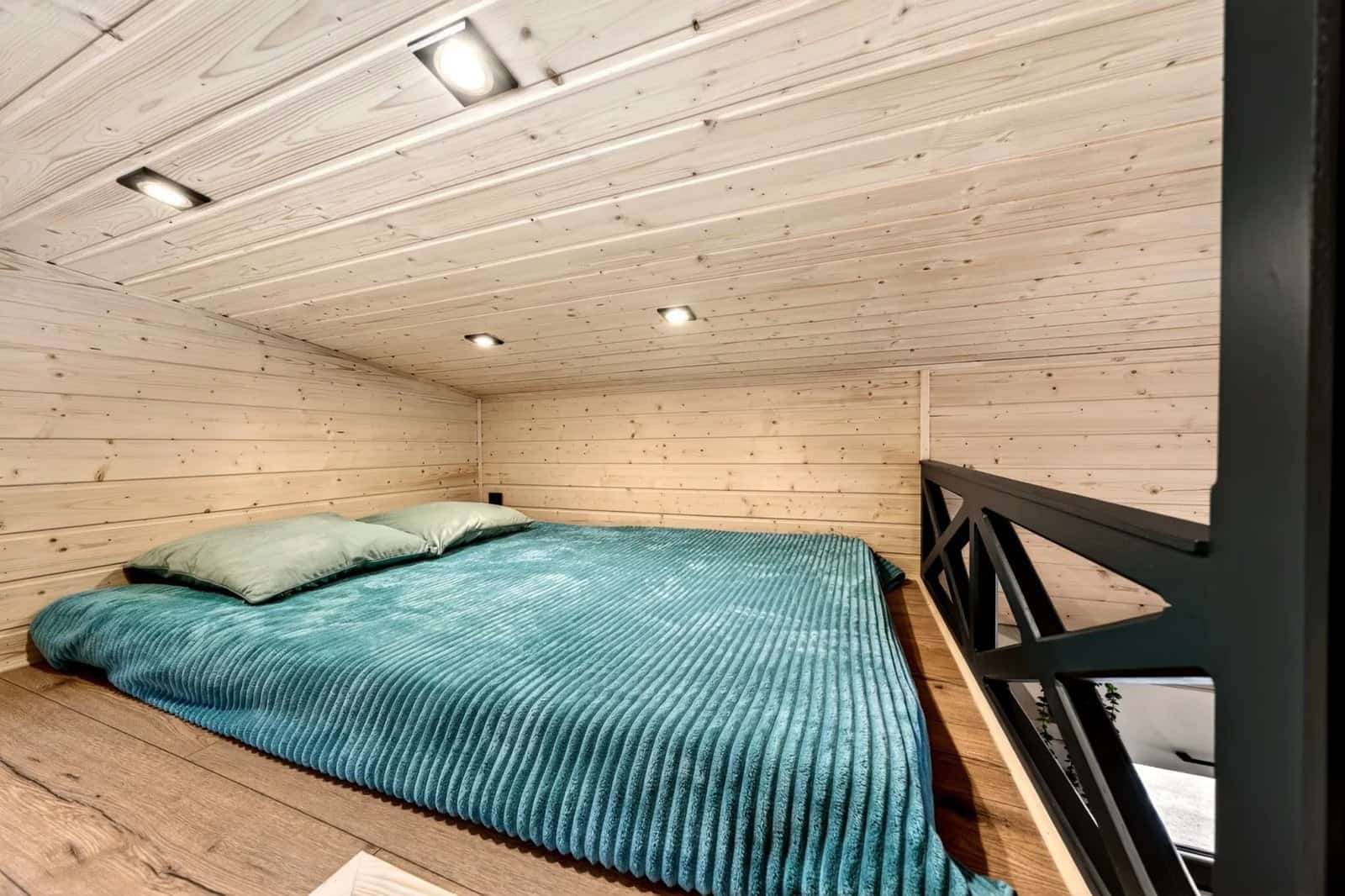 Second mezzanine sleeping loft in the Tommy tiny house with a double bed and a steel-truss railing