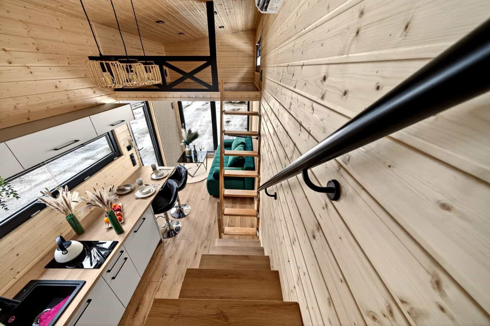 View down the staircase of the Tommy tiny house over the kitchen, dining bar, and living room