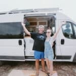 Happy couple enjoying their van conversion in a scenic outdoor setting.