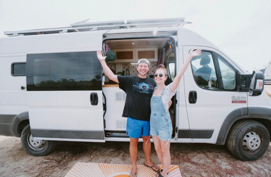 Happy couple enjoying their van conversion in a scenic outdoor setting.