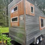 Compact tiny house with mixed wood and metal exterior.