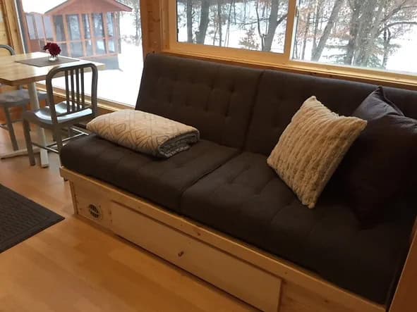 Comfortable sofa with pillows in a tiny house with lake view windows.
