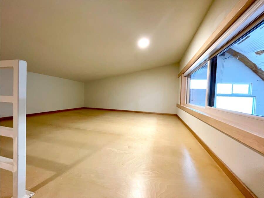 Bright interior of a tiny house with a spacious, open floor plan and a large window for natural ligh.