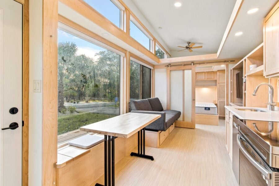 Bright tiny house interior featuring expansive windows and modern kitchen amenities.