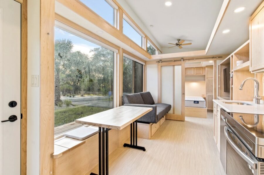 Bright tiny house interior with expansive windows and modern kitchen design.