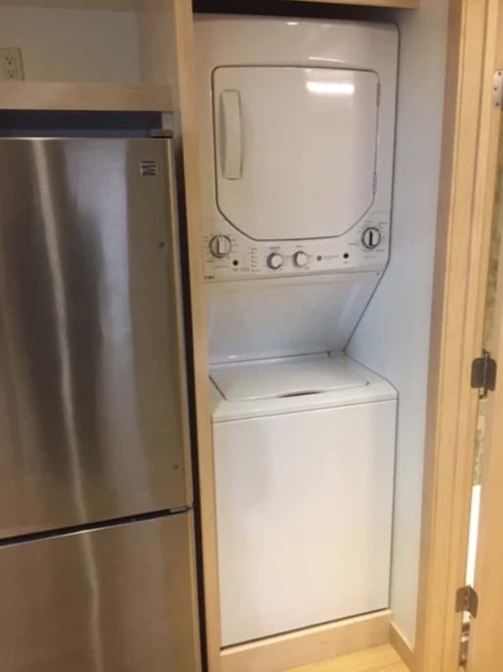 Laundry area with stacked washer and dryer in a compact tiny house space.
