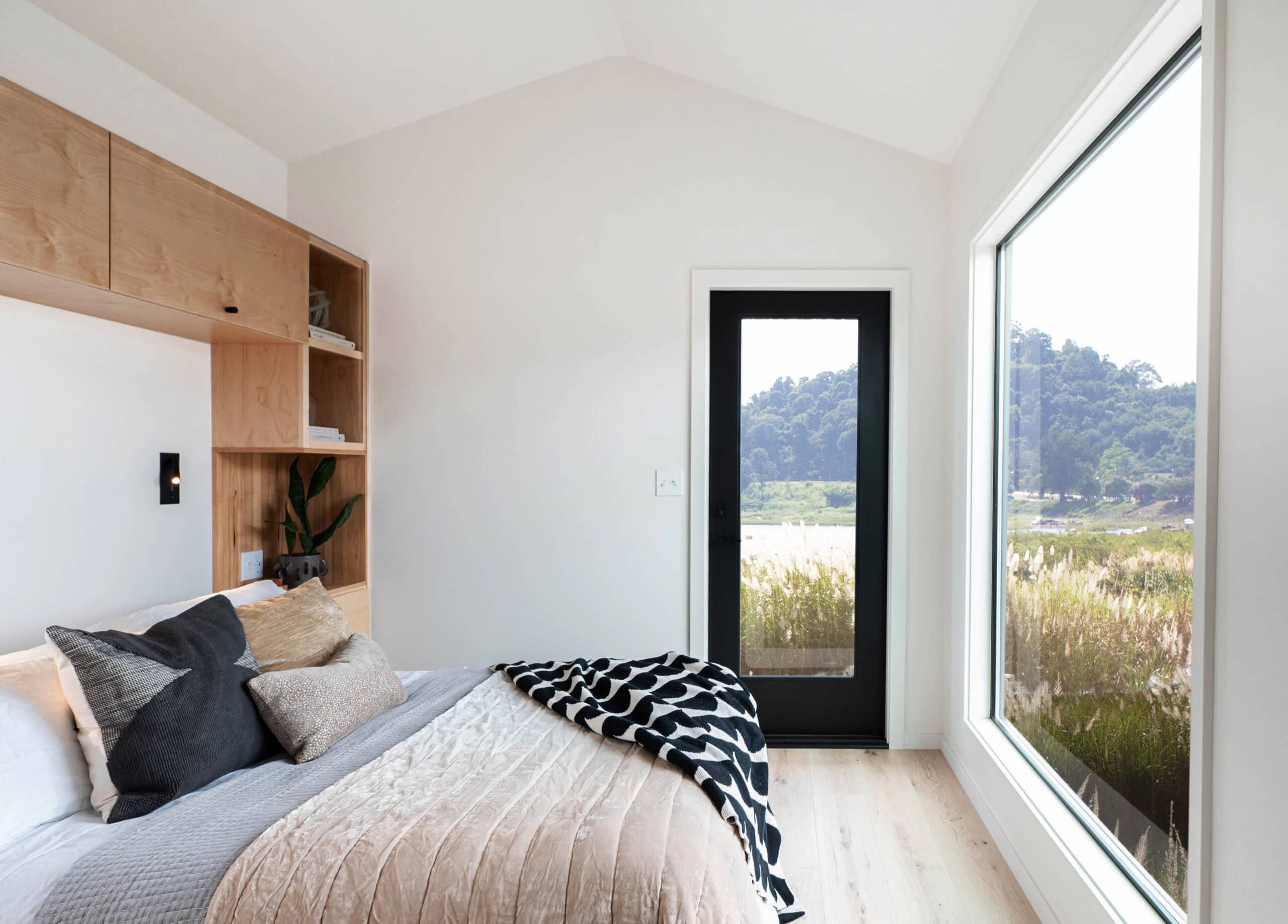 Bedroom with custom built-in headboard storage, large window, and birch closet doors
