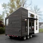 Compact tiny house on wheels with sleek black and white exterior.
